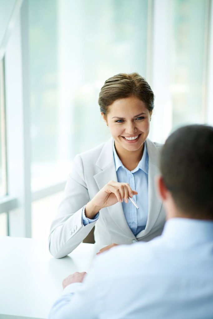 A woman conducting an interview with a male candidate in a contemporary, professional setting, showcasing CloudnData's thorough and respectful recruitment approach.